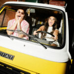 couple driving yellow fiat van